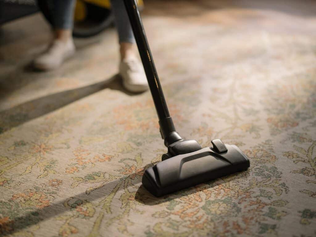 Un homme qui nettoie un tapis avec un aspirateur